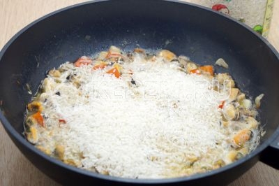 Высыпать длиннозерный рис ТМ «Алейка» и разровнять,  прикрыть крышкой и готовить на медленном огне 15-20 минут.
