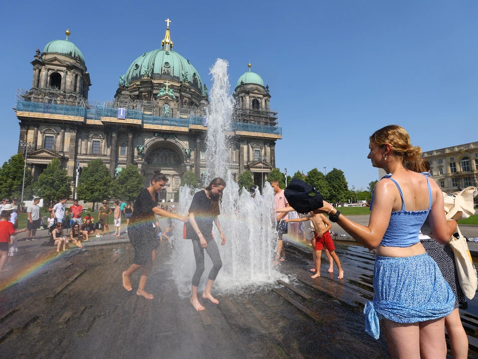 Жители Берлина охлаждаются в воде фонтана в жаркий день.